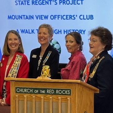 This photo shows four women in business dress wearing DAR pins. One of the women is the Regent of the Arizona State Society DAR who was attending a meeting of Oak Creek Chapter, NSDAR.