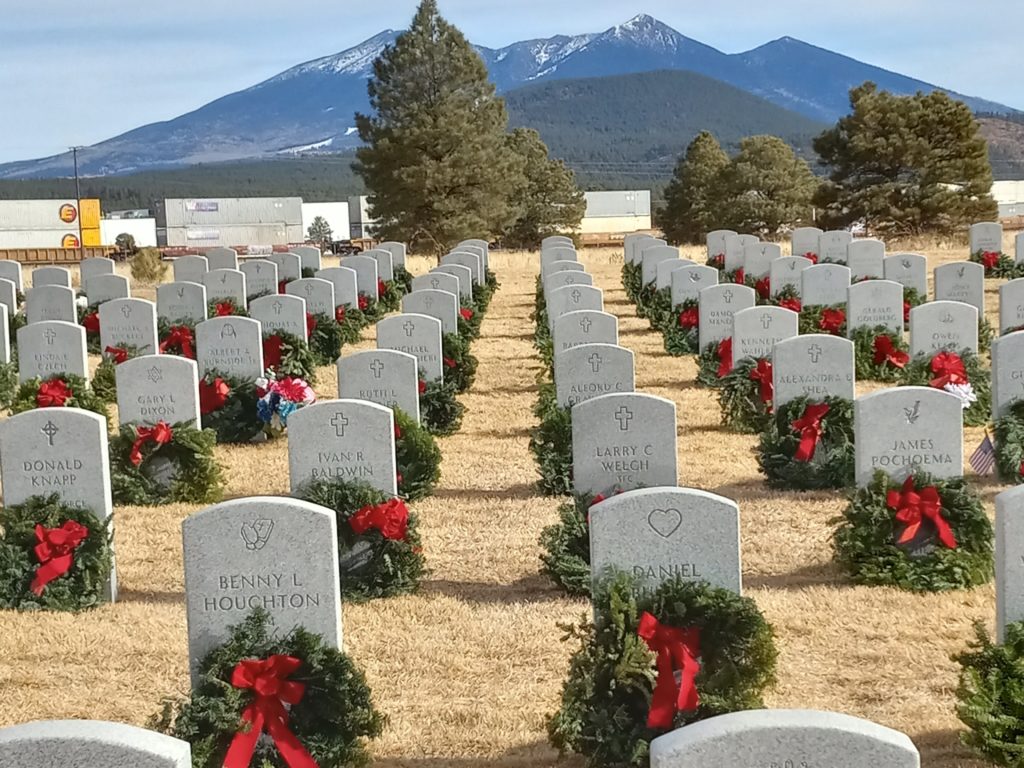 This photo shows rows of headstones with green wreaths at the Arizona Veterans' Cemetery at Camp Navajo, Bellemont, Arizona.